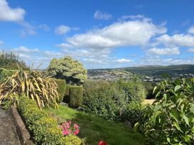 A garden with flowers and trees overlooking a valley at The White House Okehampton