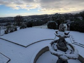 A garden with a fountain and snow at The White House in Okehampton