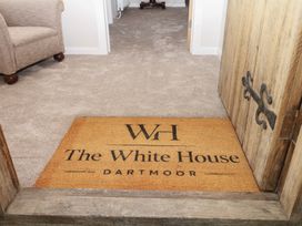 A hallway with a door mat and a couch at The White House Okehampton