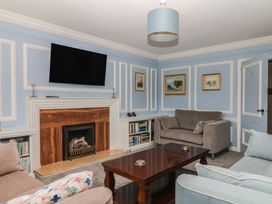 A living room with a television above a fireplace at The White House in Okehampton