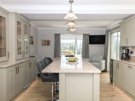 A kitchen with an island counter and bar stools at The White House in Okehampton