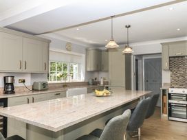 A kitchen with cabinets, island, appliances and stools at The White House in Okehampton