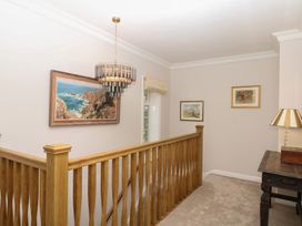 A hallway with a chandelier and paintings at The White House in Okehampton