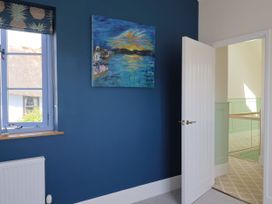 A bedroom with a blue wall and a window at Mayflower Cottage in Lyme Regis