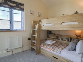 A bedroom with a bunk bed and bookshelf at Mayflower Cottage in Lyme Regis