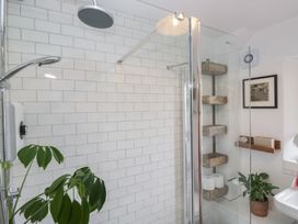 A shower with glass enclosure and shelving at Over Brow Cottage in Coniston