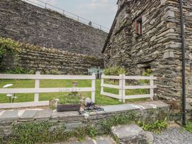 A garden with a stone wall and table and chairs at Over Brow Cottage in Coniston