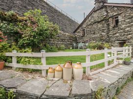 A garden with a stone wall and a fence at Over Brow Cottage in Coniston