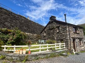 A stone house with a garden and seating area at Over Brow Cottage in Coniston