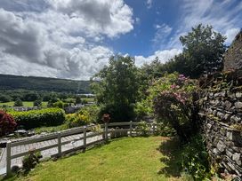 A garden with grass, flowers, and fence at Over Brow Cottage in Coniston