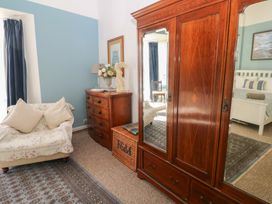A bedroom featuring a wardrobe, chest of drawers, sofa and a decorative lamp at Sea Suite