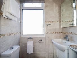 A bathroom with a sink, toilet, mirror, and towels at Two Bed Apartment No.4 Newquay
