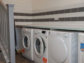 A laundry room with washing machines and a shelf at Penthouse No.3 in Newquay