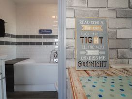 A bathroom with a bathtub and a decorative sign at Penthouse No.3 in Newquay