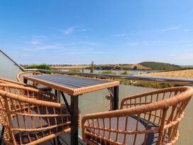 A balcony with table and chairs overlooking a landscape at Little House in Wadebridge