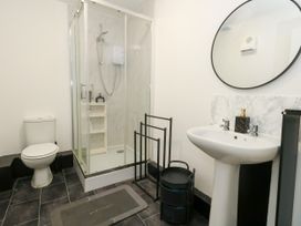 A bathroom with a shower, toilet, sink, and mirror at Ocean Breeze in Weymouth