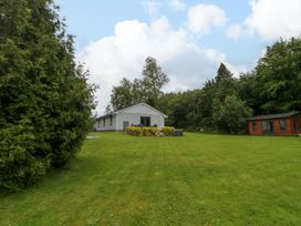 A house with green garden and trees in the background at 3 bed property
