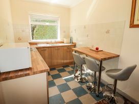 A kitchen with counters and bar stools at Cottage 1 in Tenby