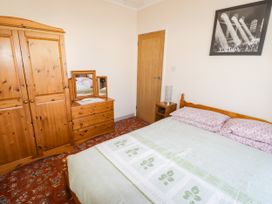 A bedroom with a bed and wooden furniture at Cottage 1 in Tenby