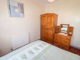 A bedroom with a bed and wooden furniture at Cottage 1 in Tenby