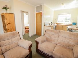 A living room with a sofa and kitchen area at Cottage 3 Tenby
