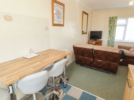A living room with a bar table and stools and a television at Cottage 3 in Tenby