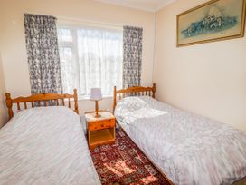 A bedroom with two beds and a side table with a lamp at Cottage 3 in Tenby