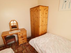 A bedroom with a wardrobe, desk, and bed at Cottage 3 in Tenby