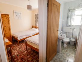 A bedroom with two beds and a bathroom with a toilet and sink at Cottage 3 in Tenby