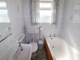 A bathroom with a bath tub and toilet at Cottage 3 in Tenby