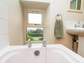 A bathroom with a bathtub, sink, and window at The Snug Glaisdale