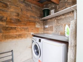 A laundry room with a washing machine and fridge at The Snug Glaisdale