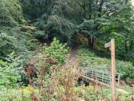 A pathway with stairs and a bridge surrounded by trees and shrubs at The Snug Glaisdale