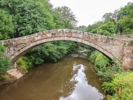 A stone bridge over a river surrounded by trees at The Snug Glaisdale in Glaisdale