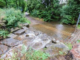A stream flowing over cobblestones beside a path in Glaisdale