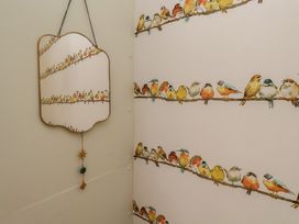 A bathroom with a bird-themed wallpaper and a mirror at 4 Studley Terrace Whitby