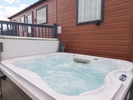 A hot tub beside a wooden cabin at Lodge - Plot 18 Near Sherburn