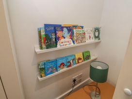 A reading nook with children's books on a shelf and a lamp at 15D Foss Street Dartmouth