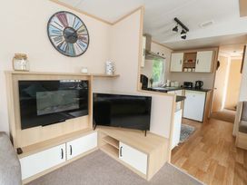 A living room with a television and kitchen area at Foxglove 4 in Ringwood