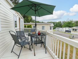 A patio with a table and chairs under an umbrella at Foxglove 4 Ringwood