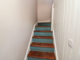 A staircase with wooden steps and a white wall at Abinas Kenmare