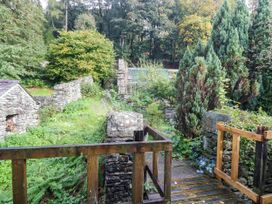 A garden with stone walls and trees at Dunmail Raise, Grasmere Lodge in Grasmere