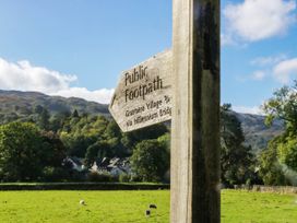 A signpost indicating public footpath to Grasmere Village via Millennium Bridge