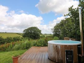 An outdoor space with a hot tub and wooden deck at Reddaway Byre Okehampton