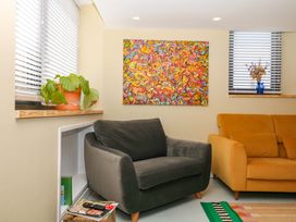 A living room with an armchair, sofa, and plant at Reddaway Byre Okehampton