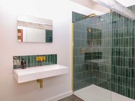 A bathroom with a mirror, sink, and shower at Reddaway Byre in Okehampton