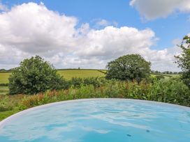 A pool with a view of trees and fields at Reddaway Byre in Okehampton
