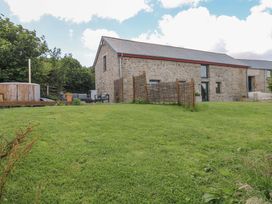 An outdoor view of a house with stone walls and a hot tub at Reddaway Byre Okehampton