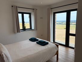 A bedroom with a bed and windows overlooking a landscape at High View Barn in Launceston