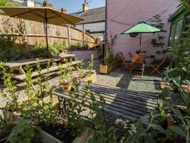 A garden with wooden tables, chairs, and planters at 11b Market Street Narberth